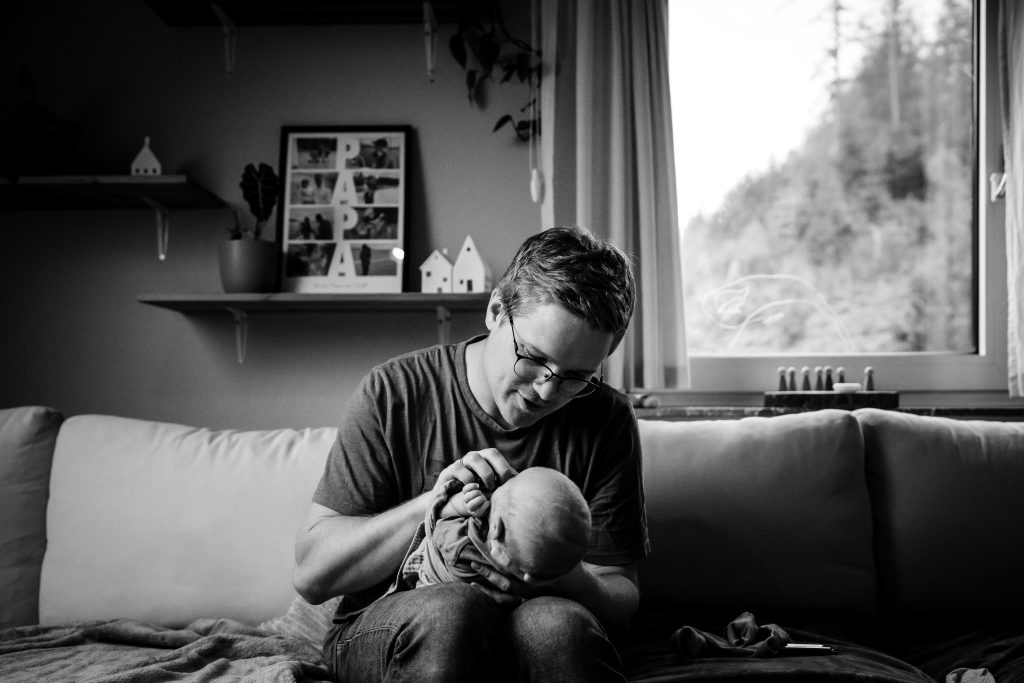 Ein Vater schaut seine kleine Tochter verliebt an während sie in seinem Schoß liegt.